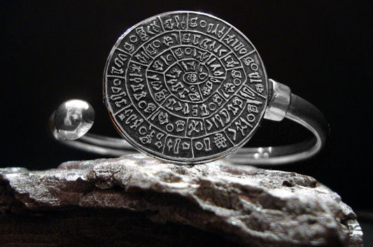 Phaistos Disc Cuff Bracelet on a silver rock with black background.